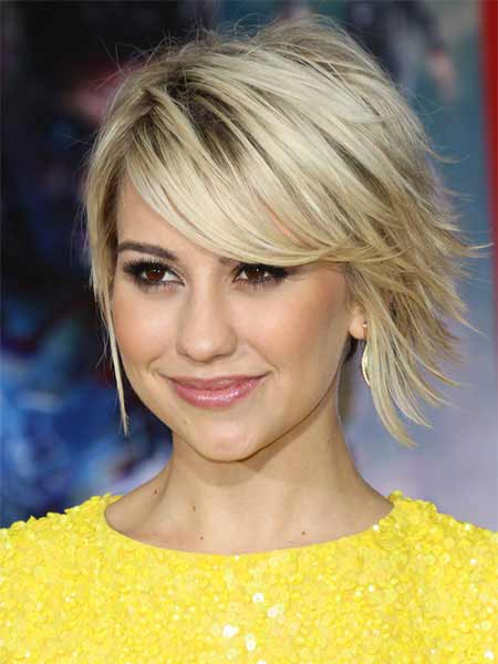 choppy layered haircut in blonde with darker root showing through and strong side bangs
