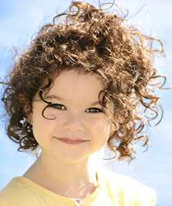 a beautiful little girl with curly frizzy hair in beach